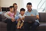 Parents and kids using laptop in living room