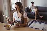 Woman using digital tablet while having breakfast