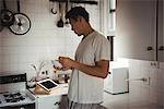 Man having breakfast while looking at digital tablet in kitchen