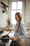 Woman preparing noodles in kitchen