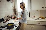 Woman preparing noodles in kitchen