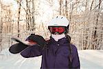 Woman in ski wear holding skis on her shoulder