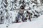 Female snowboarder jumping over the slope