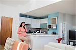 Pregnant woman talking on mobile phone in kitchen