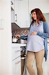 Pregnant woman cooking food in kitchen