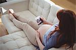 Pregnant woman relaxing on sofa and looking at sonography