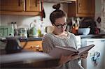 Woman reading book in kitchen