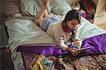 Woman using digital tablet while having coffee on bed