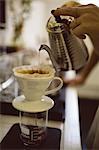 Female barista hands pouring hot water through funnel in coffee shop