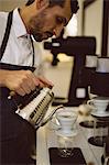 Barista pouring hot water through funnel in coffee shop