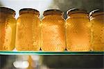 Close-up of honey and honeycomb in glass jars on shelf at supermarket