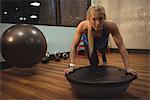 Fit woman exercising with bosu ball in the gym