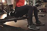 Fit woman exercising with dumbbells on a machine in the gym