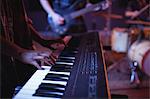 Mid section of musician playing electronic piano in recording studio