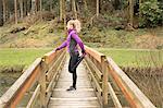 Woman performing stretching exercise on the bridge in forest
