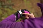 Mid section of woman using smart watch in the forest