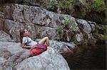 Young woman relaxing on a rock in countryside