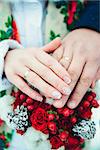 Bridal hands with rings on a bouquet of berries and cones with shallow depth of field