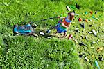 Young girl pushing a lawnmower cutting grass and leaving plastic litter behind - top view