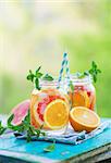 Water detox with Grapefruit and Orange in Jars, Outdoor. Refreshing summer drink. Copy space.