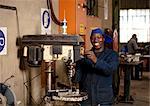 Factory worker operating drill press in magnet factory, Gauteng, South Africa