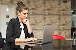 Young businesswoman looking at laptop on office desk