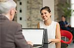 Young businesswoman and female colleague talking over office desk