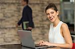 Young businesswoman typing on laptop at office desk