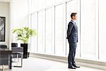 Confident businessman looking through office window