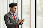 Businessman looking using smartphone touchscreen by office window