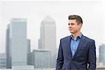 Confident  businessman gazing from city office roof terrace, London, UK