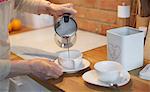 Senior adult woman pouring coffee into cups