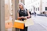 Stylish mature female shopper gazing at shop window, Florence, Italy