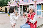 Mature woman and girl eating ice cream cones outside ice cream parlour, Florence, Italy