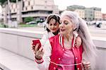 Mature woman and girl selecting headphone music in city