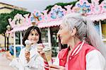 Mature woman and girl eating ice cream cones outside ice cream parlour, Florence, Italy