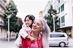 Mature woman giving girl piggyback in city