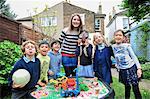 Portrait of childminder and children by sandpit looking at camera smiling