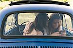 Friends in vintage car looking at smartphone smiling, Firenze, Toscana, Italy, Europe