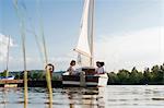 Three friends relaxing on sailing boat on lake