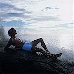 Man lying on rock in sea looking away, China Bay, Sri Lanka, Asia