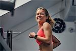 Young woman training, running on gym treadmill looking over her shoulder