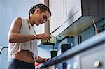 Young woman pouring smoothie at kitchen counter