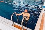 Senior man using ladder in swimming pool