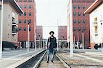 Portrait of young male hipster standing on city tram lines