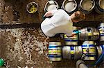 Directly above view of a man working in a brewery, metal beer kegs standing on the floor.