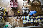 Directly above view of a man working in a brewery, metal beer kegs standing on the floor.