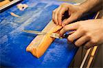 Close up high angle view of person, cutting a fillet of salmon on a blue chopping board.