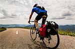 Rear view of man riding bicycle on road