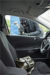 Thief breaking into a car using hammer